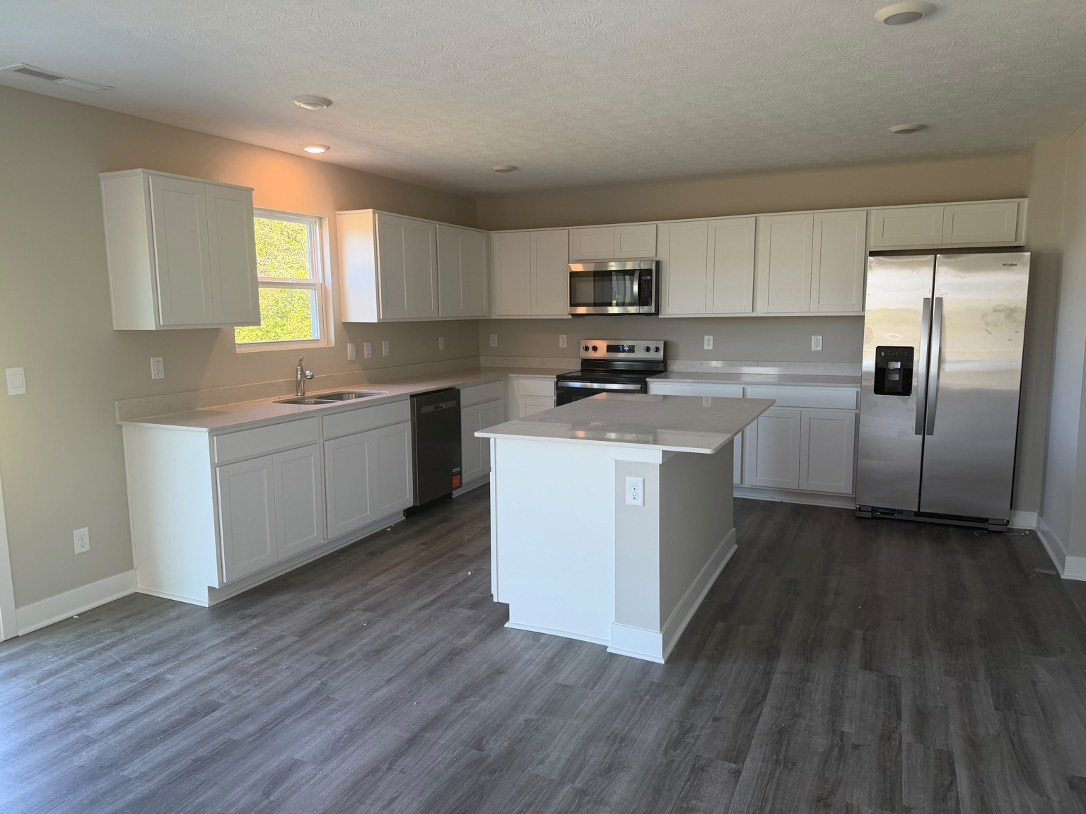 Kitchen with white cabinetry, quartz countertops and island
