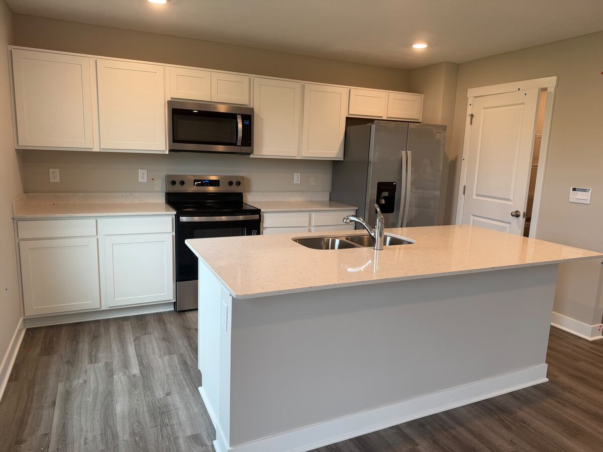 Kitchen with white cabinetry, quartz countertops, island and stainless-steel appliances